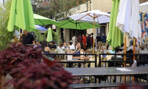 a group of people sitting at tables under umbrellas